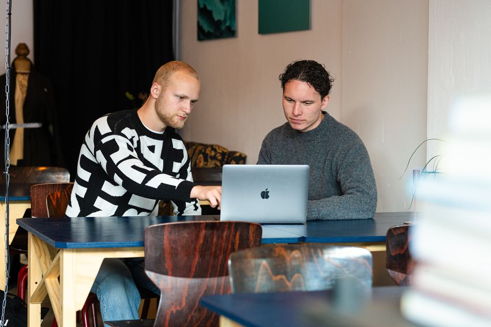Jasper en Pim van Studio JAPI werken samen aan een laptop aan een tafel in een creatieve werkruimte